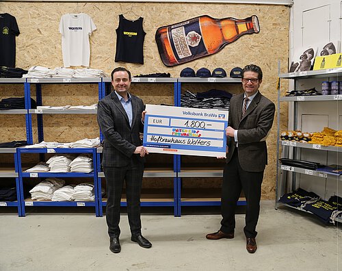 Francesco Perricone (l.), Geschäftsführer des Hofbrauhaus Wolters, übergibt die Spende stilecht im Wolters Fanshop an Carsten Ueberschär, Botschafter von United Kids Foundations und Leitung der Direktion Braunschweig. Foto: Volksbank BraWo