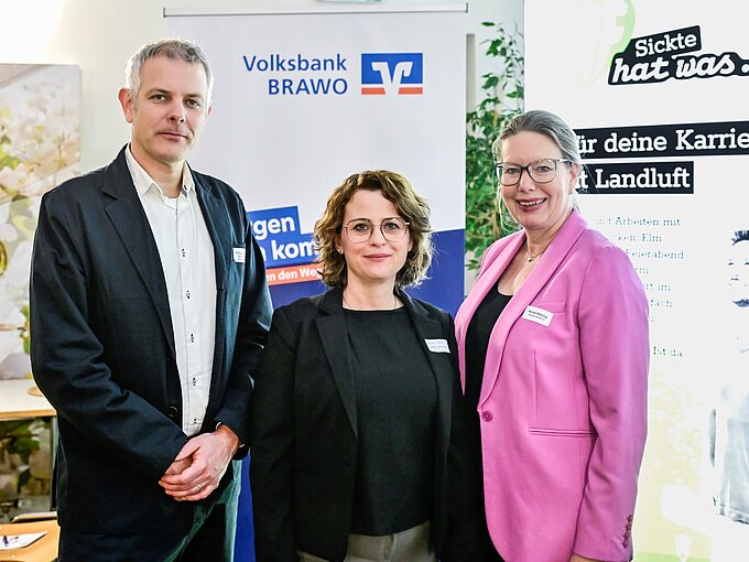 Drei Personen posieren vor einem Volksbank BRAVO und Karriere-Event-Banner.