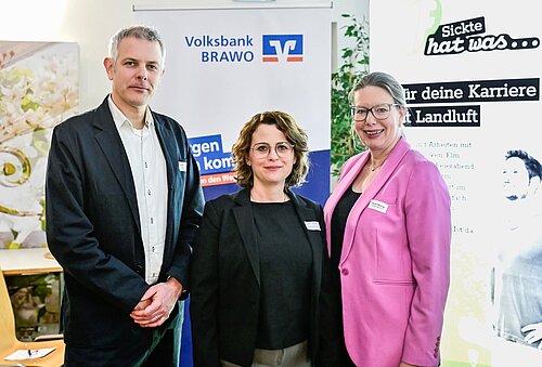 Drei Personen posieren vor einem Volksbank BRAVO und Karriere-Event-Banner.