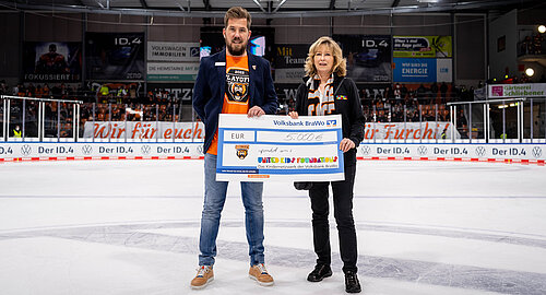 Simon Drühmel, Leiter Sales der Grizzlys Wolfsburg, übergibt den symbolischen Spendenscheck des Charity-Spieltags über 5.000 Euro an Claudia Kayser, Leitung der Direktion Wolfsburg. Foto: City-Press GmbH