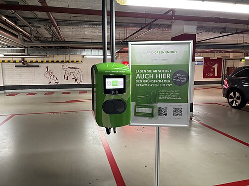 Ladestation für Elektroautos in einer Tiefgarage mit Werbung für Brawo Green Energy Grünstrom.
