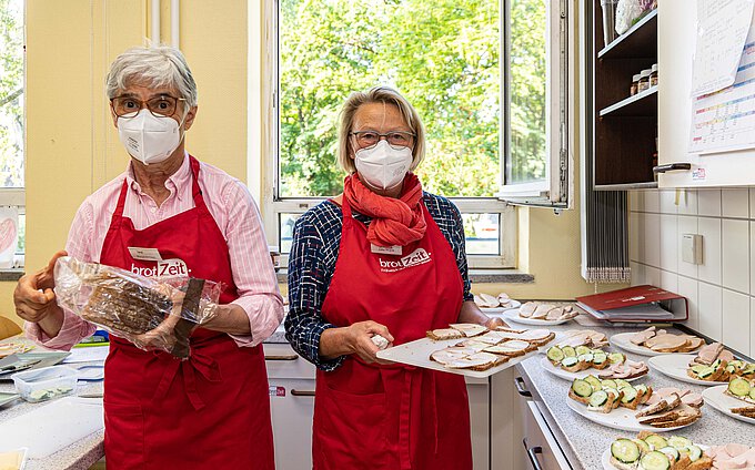 Ehrenamtliche Seniorinnen und Senioren wie Margit Meinert (l.) und Jutta Wojcik bereiten das gesunde Frühstück zu und verteilen es an die Kinder. Foto: Rudolf Karliczek Ehrenamtliche Seniorinnen und Senioren wie Margit Meinert (l.) und Jutta Wojcik bereiten das gesunde Frühstück zu und verteilen es an die Kinder. Foto: Rudolf Karliczek