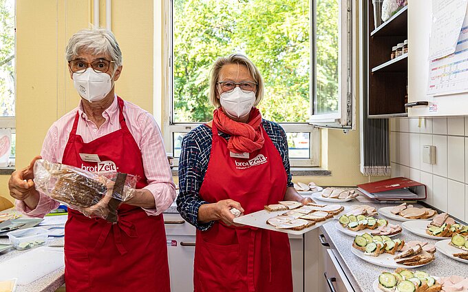 Ehrenamtliche Seniorinnen und Senioren wie Margit Meinert (l.) und Jutta Wojcik bereiten das gesunde Frühstück zu und verteilen es an die Kinder. Foto: Rudolf Karliczek Ehrenamtliche Seniorinnen und Senioren wie Margit Meinert (l.) und Jutta Wojcik bereiten das gesunde Frühstück zu und verteilen es an die Kinder. Foto: Rudolf Karliczek