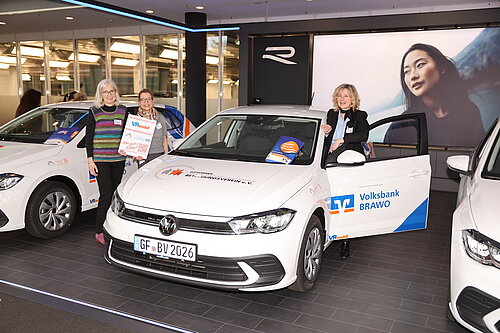 Drei Personen präsentieren einen VW Polo der Volksbank BRAWO bei einer VRmobil-Veranstaltung im Ausstellungsraum.
