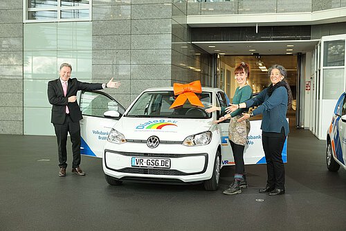 Thomas Fast, Leiter der Direktion Gifhorn der Volksbank BraWo, übergibt das VRmobil an Julia Hüffmeyer und Daniela Cevik (r.) vom Dialog e.V.