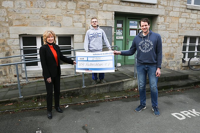 Claudia Kayser übergibt den symbolischen Spendenscheck an Dr. Nicolas Heidtke (r.), 1. Vorsitzender des VfB Fallersleben, und Tom-Lukas Behrens (Mitte), Spieler der 2. Herren Fußball. Foto: Volksbank BraWo / Cagla Canidar / KURT Media