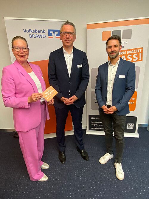 Die Organisatoren der Veranstaltung Nicole Mölling, links, und Alexander Spormann, rechts, stehen vor zwei Flip-Charts und in der Mitte steht der Referent Ansgar Nolte.