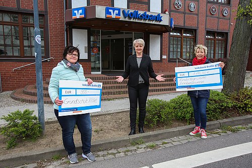 Michaela Wiewall (Mitte) übergibt die Spenden symbolisch an Dana Saalfeld (l.), Schulleiterin der Purnitz-Schule Klötze, und Christine Paul, Leiterin der Kindertagesstätte Zinnbergzwerge. Foto: Volksbank BraWo / Michael Uhmeyer / KURT Media