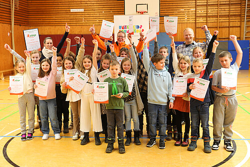 Die Kinder freuen sich über ihre Siegerurkunden, 250 Euro Preisgeld für die Klassenkasse und den Pokal.