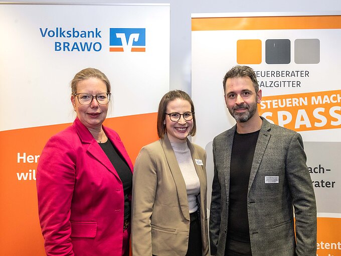 Drei Personen vor Bannern der Volksbank Brawo und Steuerberater Salzgitter lächeln in die Kamera.