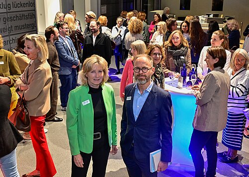Menschen versammeln sich in einem lichtdurchfluteten Raum für ein gesellschaftliches Event oder eine Networking-Veranstaltung.