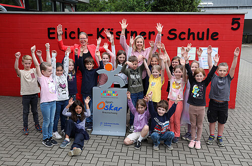 Die Schülerinnen und Schüler der Erich-Kästner-Schule in Weddel freuen sich über die Sport-Oskar Trophäe, die ihnen von Nicole Mölling, Botschafterin von United Kids Foundations, übergeben wurde
