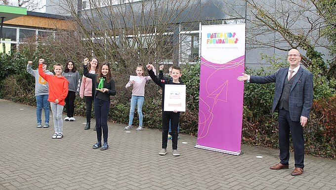 Die anwesenden Schülerinnen und Schüler der Klasse 4c der Hainwaldschule Vöhrum freuen sich mit Klassenlehrerin und step BraWo-Coach Frau Baars über den Pokal des step-BraWo Direktionssiegers in Peine, übergeben von Stefan Honrath (r.).