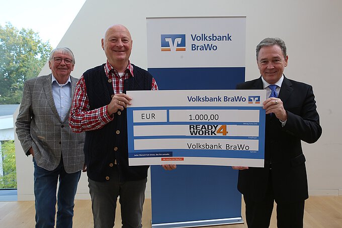 Klaus-Jürgen Herzberg (M.), Vorstandsmitglied bei ready4work, nimmt im Beisein vom ehemaligen Vereinsvorstand Albrecht Düsel (l.) die Spende von Thomas Fast, Leiter der Direktion Gifhorn, entgegen. Foto: Volksbank BraWo / Michael Uhmeyer/KURT Media